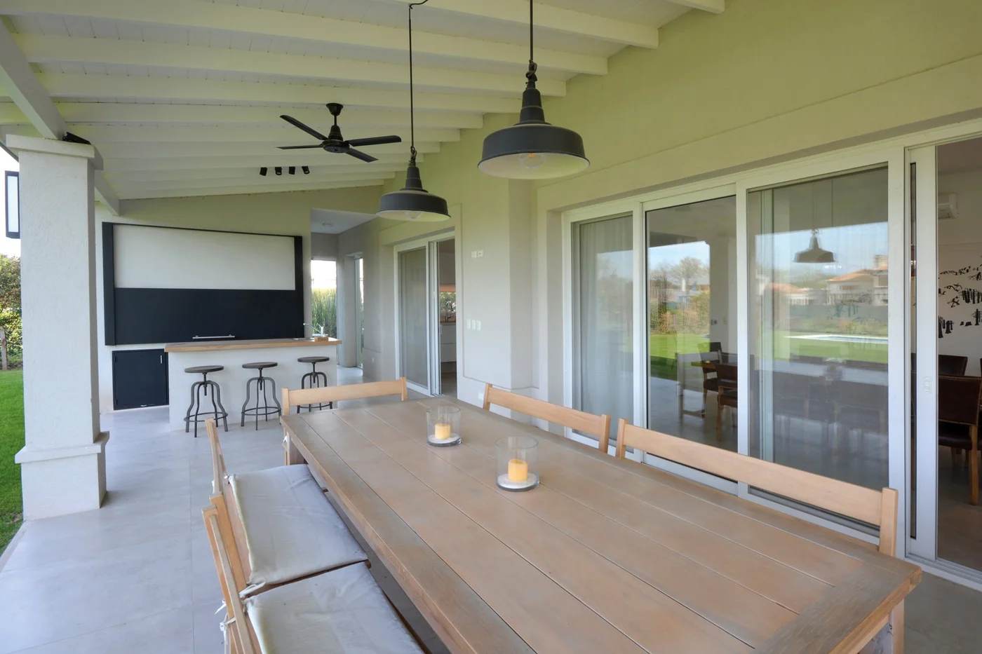 Galería con comedor, piso pulido y aberturas vidriadas al jardín