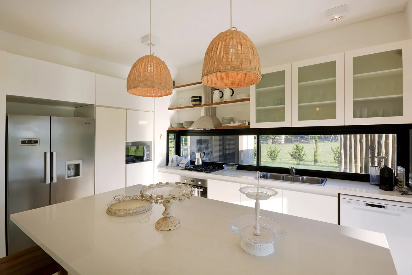 Cocina moderna con isla central, lámparas colgantes y ventanal luminoso