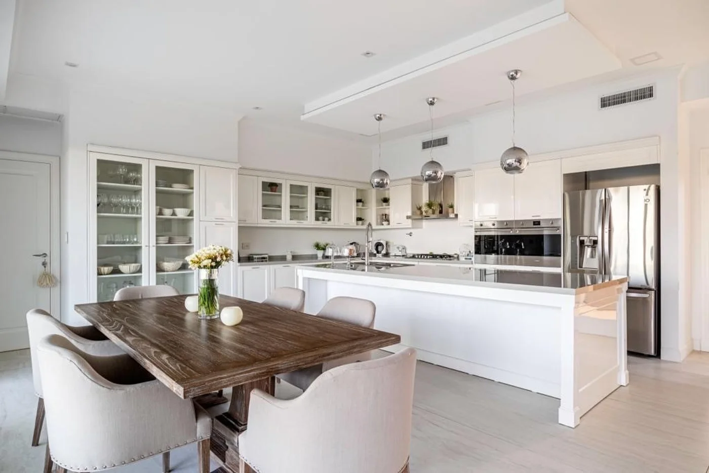 Cocina blanca minimalista con isla de mármol y muebles de madera.