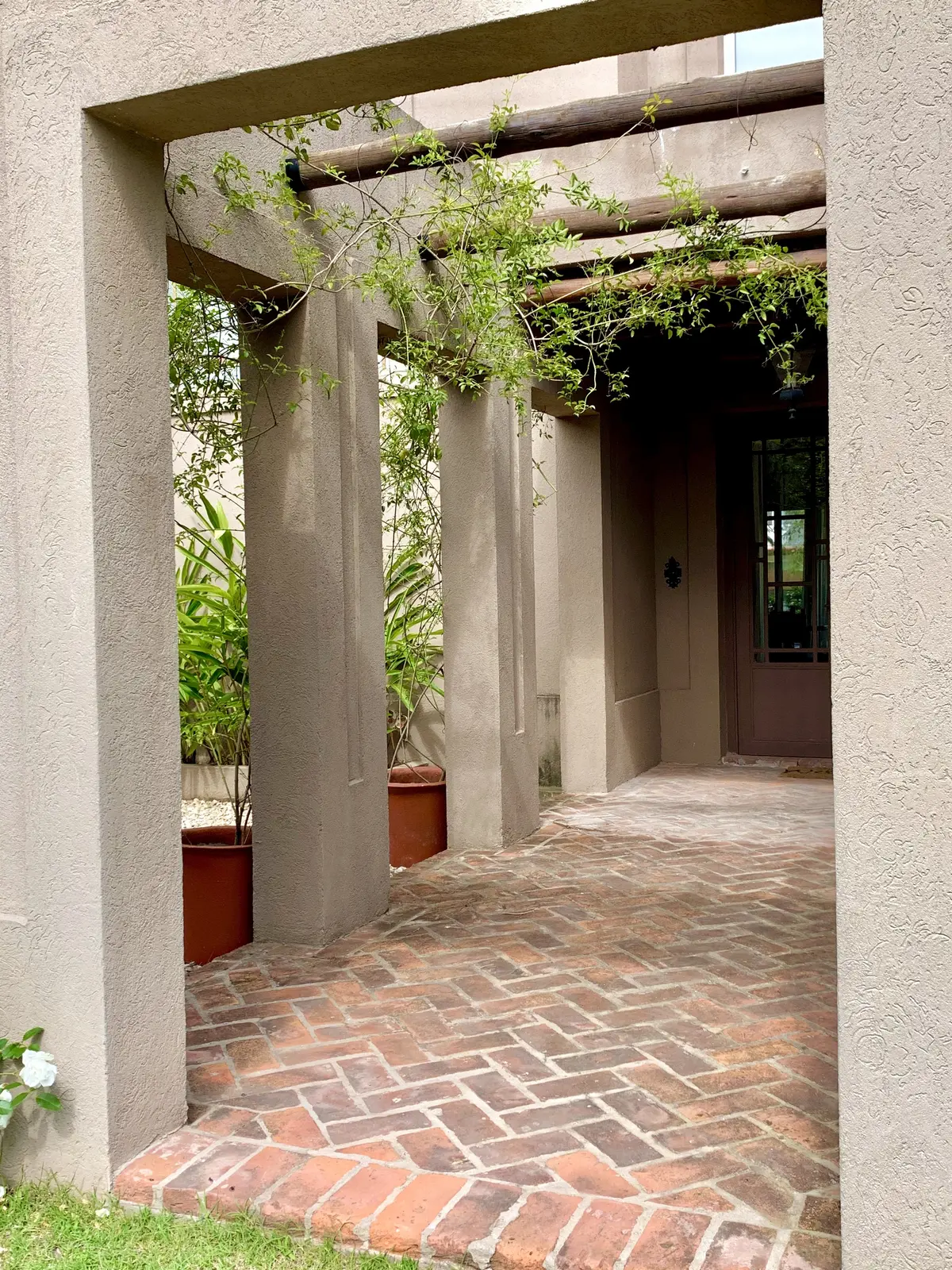 Galería cubierta con columnas hormigón y piso ladrillo herringbone — proyecto El Encuentro , por Marconi Silva Arquitectos, en Benavidez