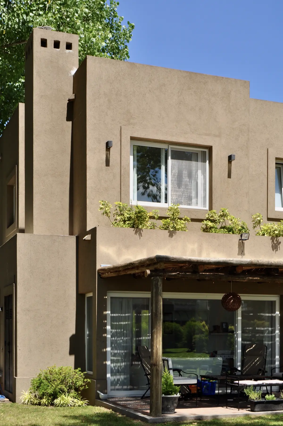 Casa contemporánea con torre, fachada hormigón y galería de madera cubierta — proyecto El Encuentro  2, por Marconi Silva Arquitectos, en Benavidez