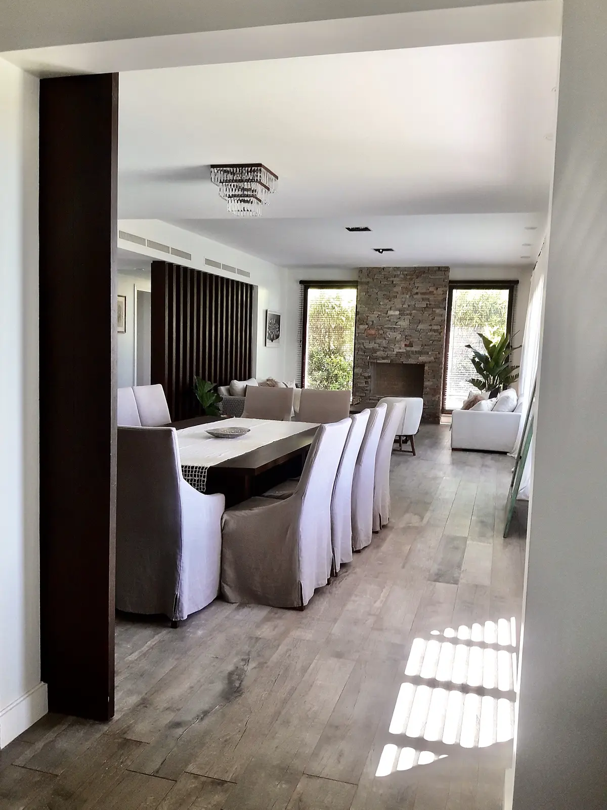 Comedor moderno con mesa negra, sillas tapizadas blancas, pared ladrillo — proyecto Golf Club Nordelta, por Marconi Silva Arquitectos, en Nordelta