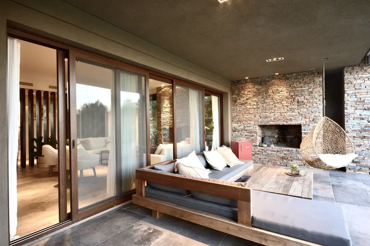 Terraza moderna con cama, chimenea ladrillo y vistas al bosque — proyecto Golf Club Nordelta, por Marconi Silva Arquitectos, en Nordelta