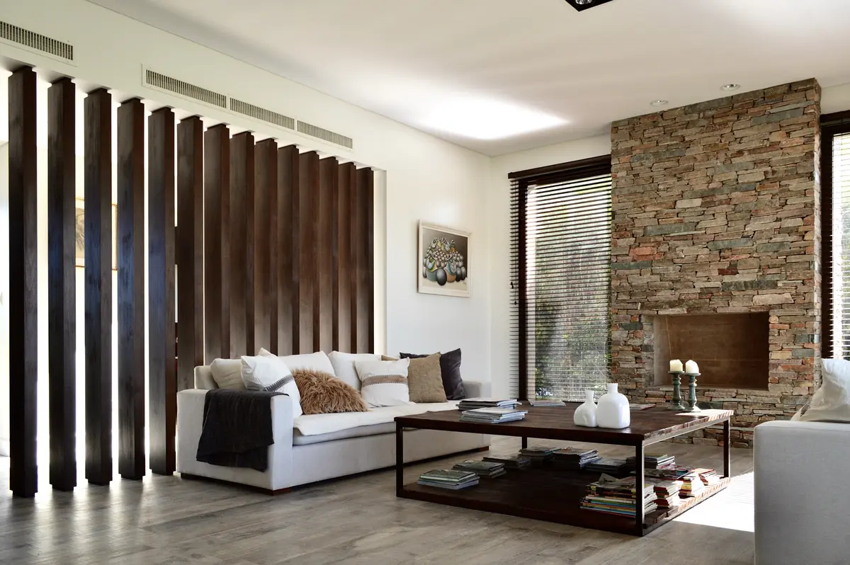 Living contemporáneo con cortinas verticales, sofá blanco y chimenea de ladrillo — proyecto Golf Club Nordelta, por Marconi Silva Arquitectos, en Nordelta