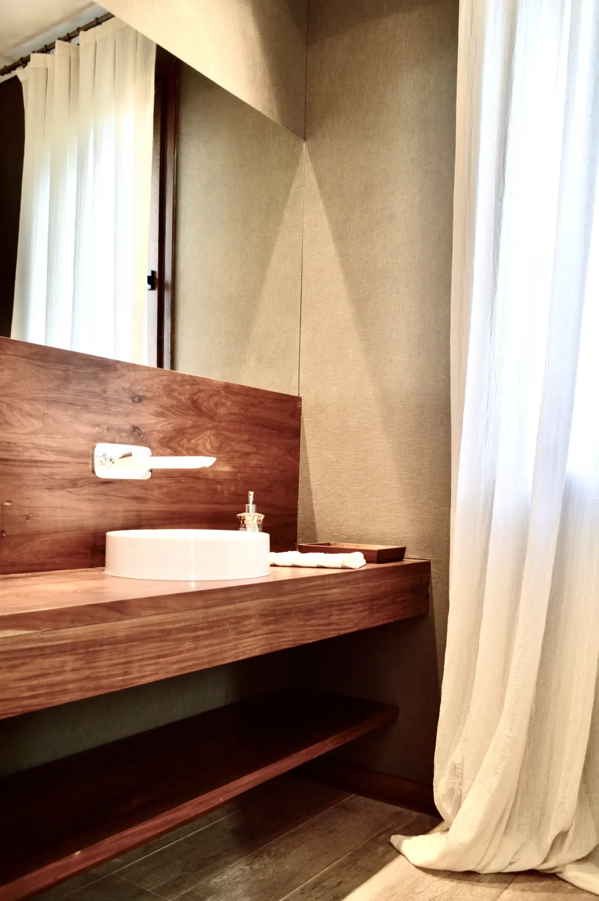Baño con mesada de madera, pileta redonda blanca y cortinas de lino — proyecto Golf Club Nordelta, por Marconi Silva Arquitectos, en Nordelta