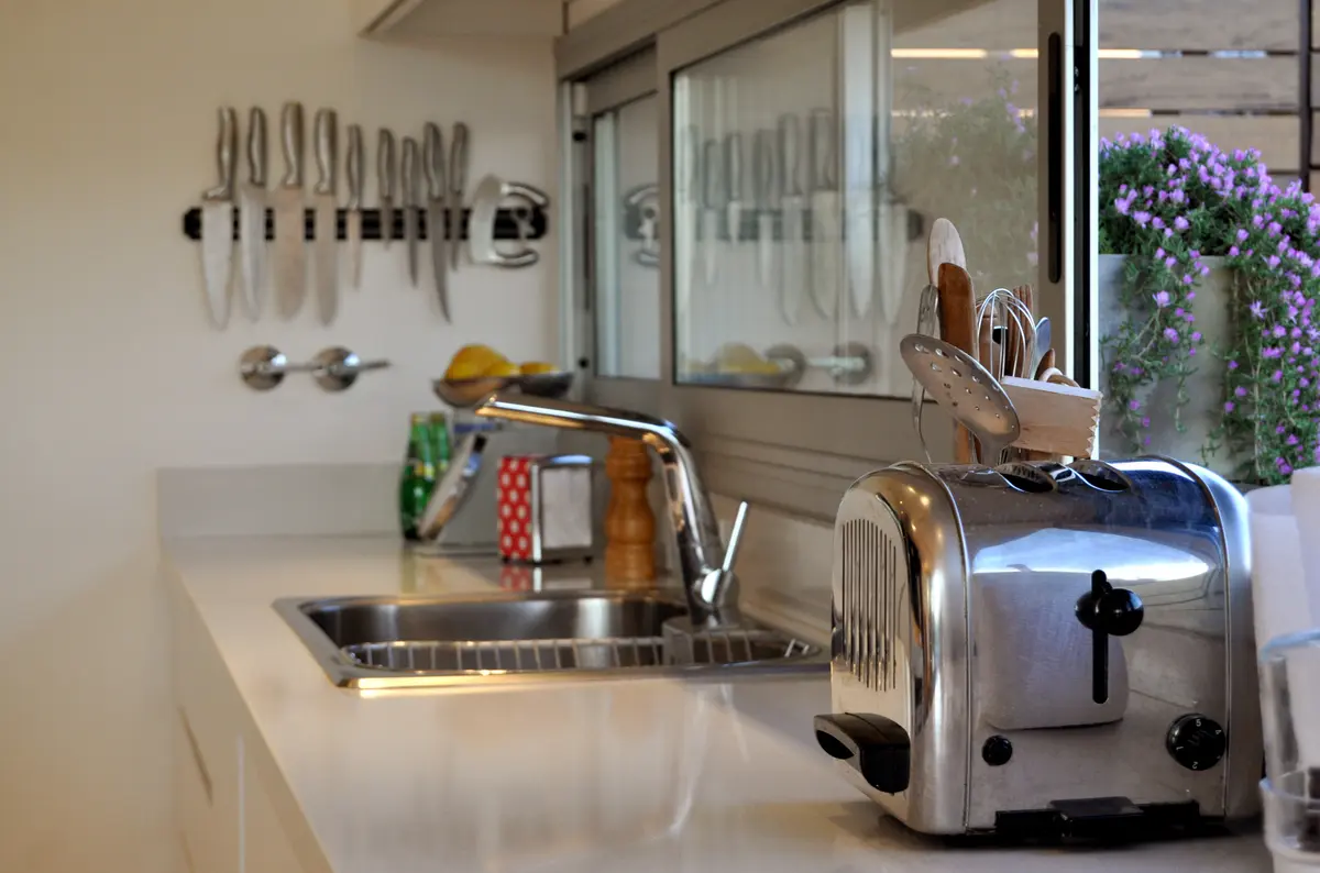 Cocina moderna con mesada blanca, tostadora plateada y ventanas amplias — proyecto Haras Santa María, por Marconi Silva Arquitectos, en Escobar