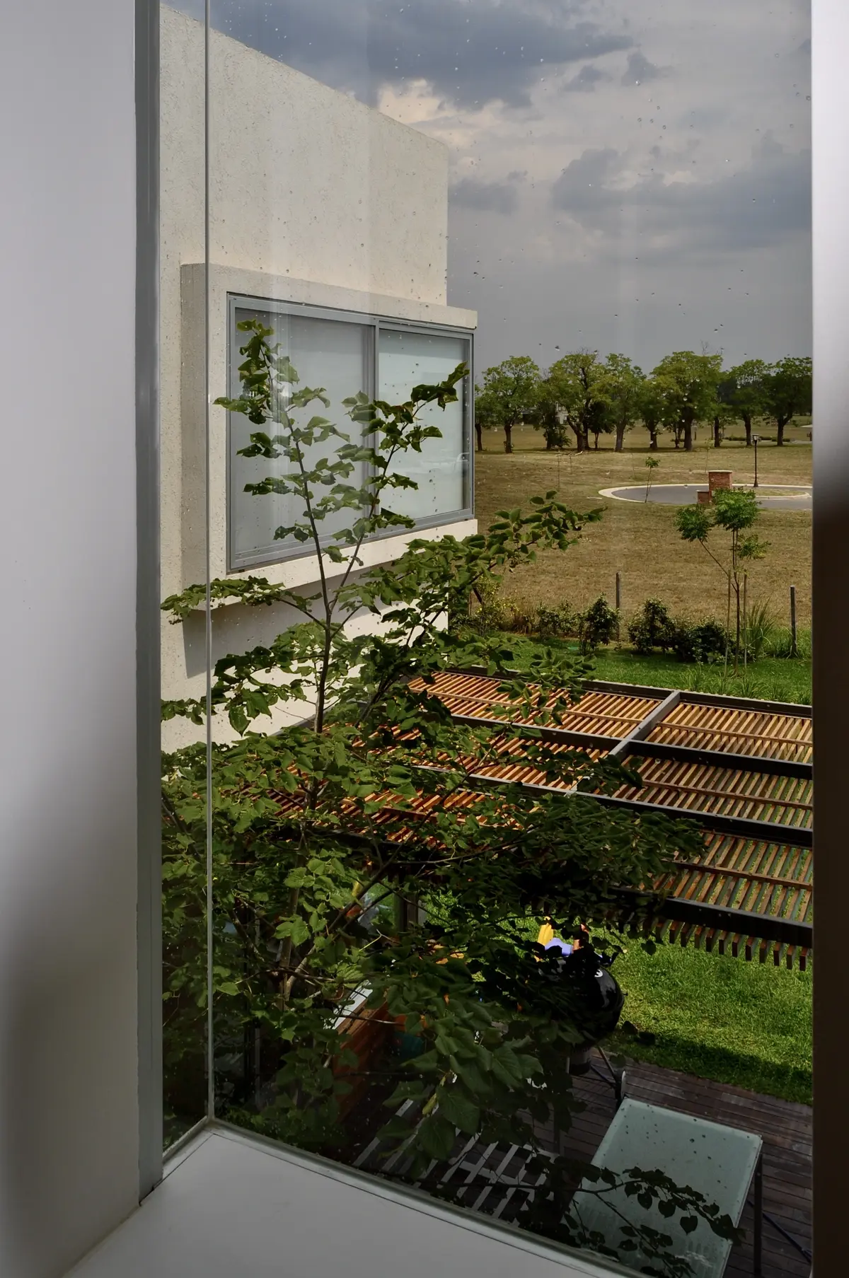 Terraza minimalista con pergola de madera y campo al fondo — proyecto Haras Santa María, por Marconi Silva Arquitectos, en Escobar