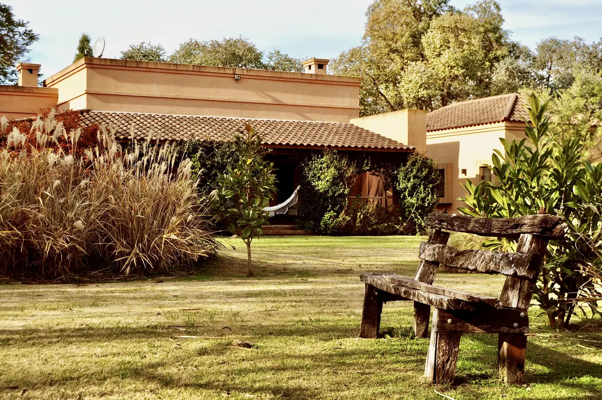 Patio con muebles rusticos, pergola y jardin exuberante, estancia acogedora — proyecto La Retama, por Marconi Silva Arquitectos, en Manzanares