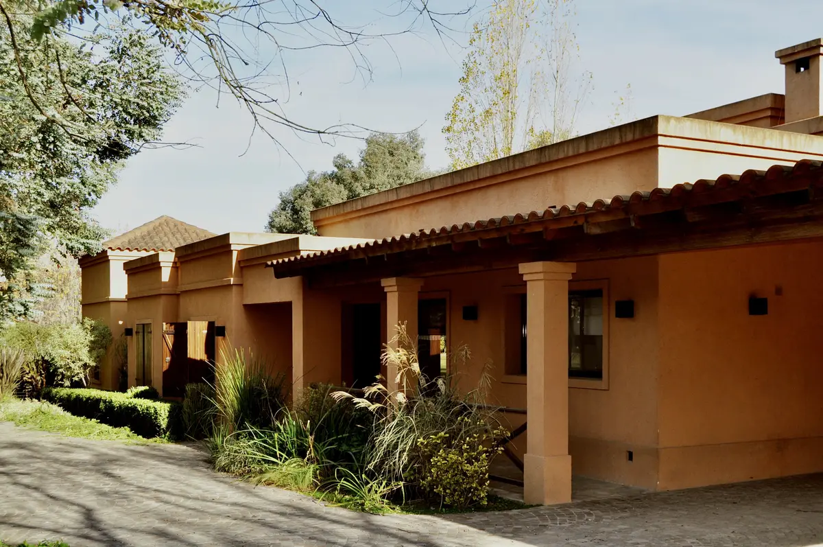 Casa de estilo mediterráneo con fachada terracota y galería cubierta — proyecto La Retama, por Marconi Silva Arquitectos, en Manzanares