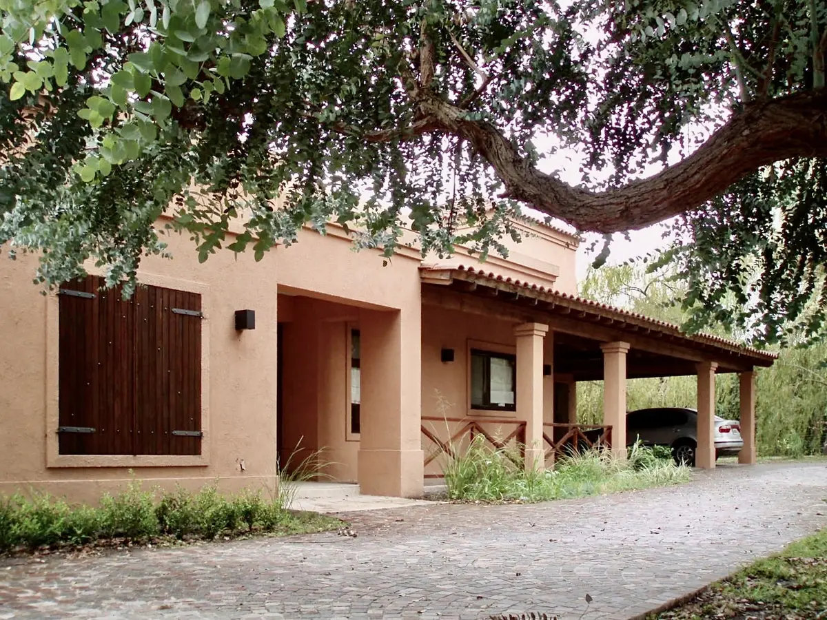 Casona colonial con fachada terracota, galería cubierta y vegetación natural — proyecto La Retama, por Marconi Silva Arquitectos, en Manzanares
