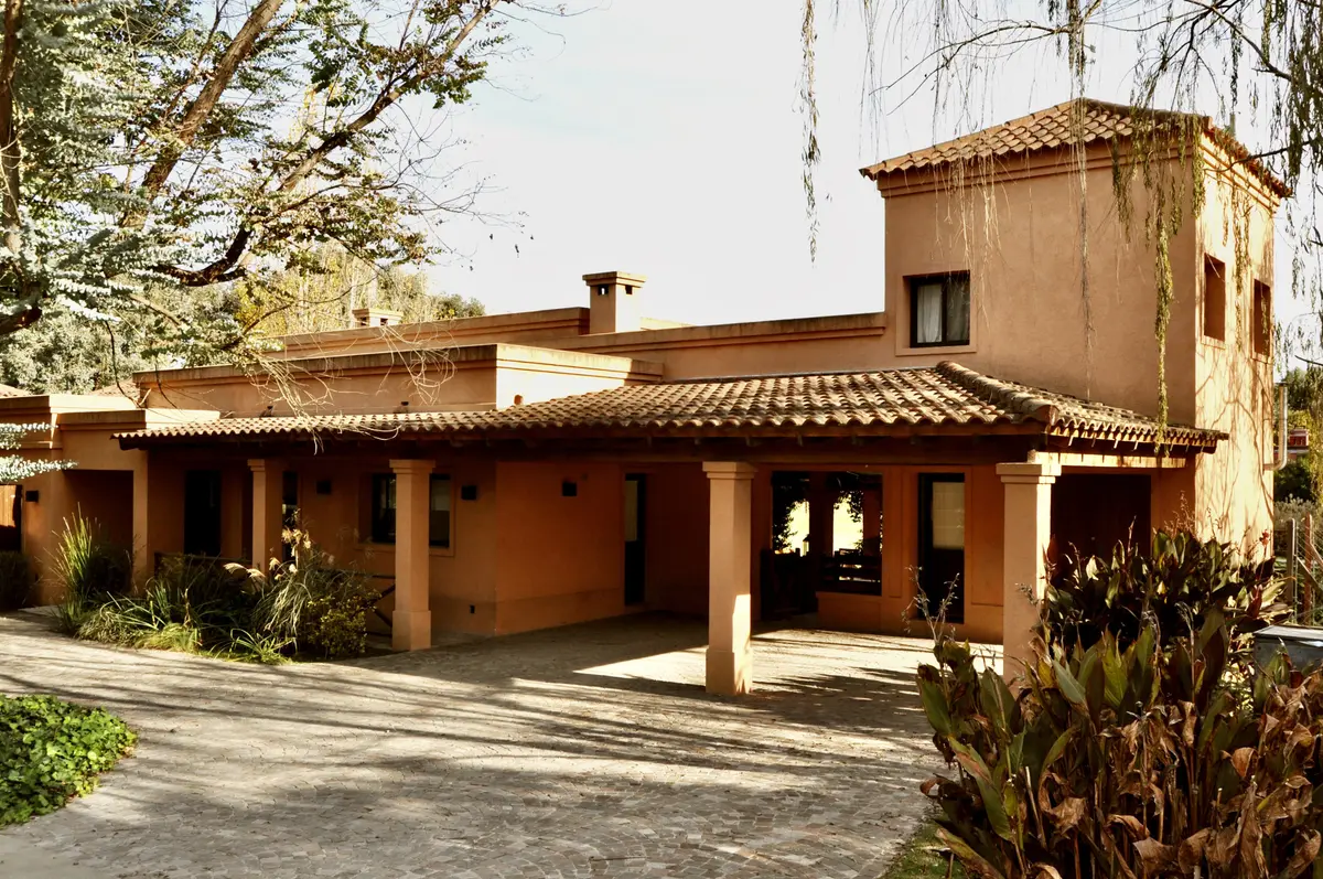 Casa estilo mediterraneo con fachada terracota y galeria cubierta — proyecto La Retama, por Marconi Silva Arquitectos, en Manzanares