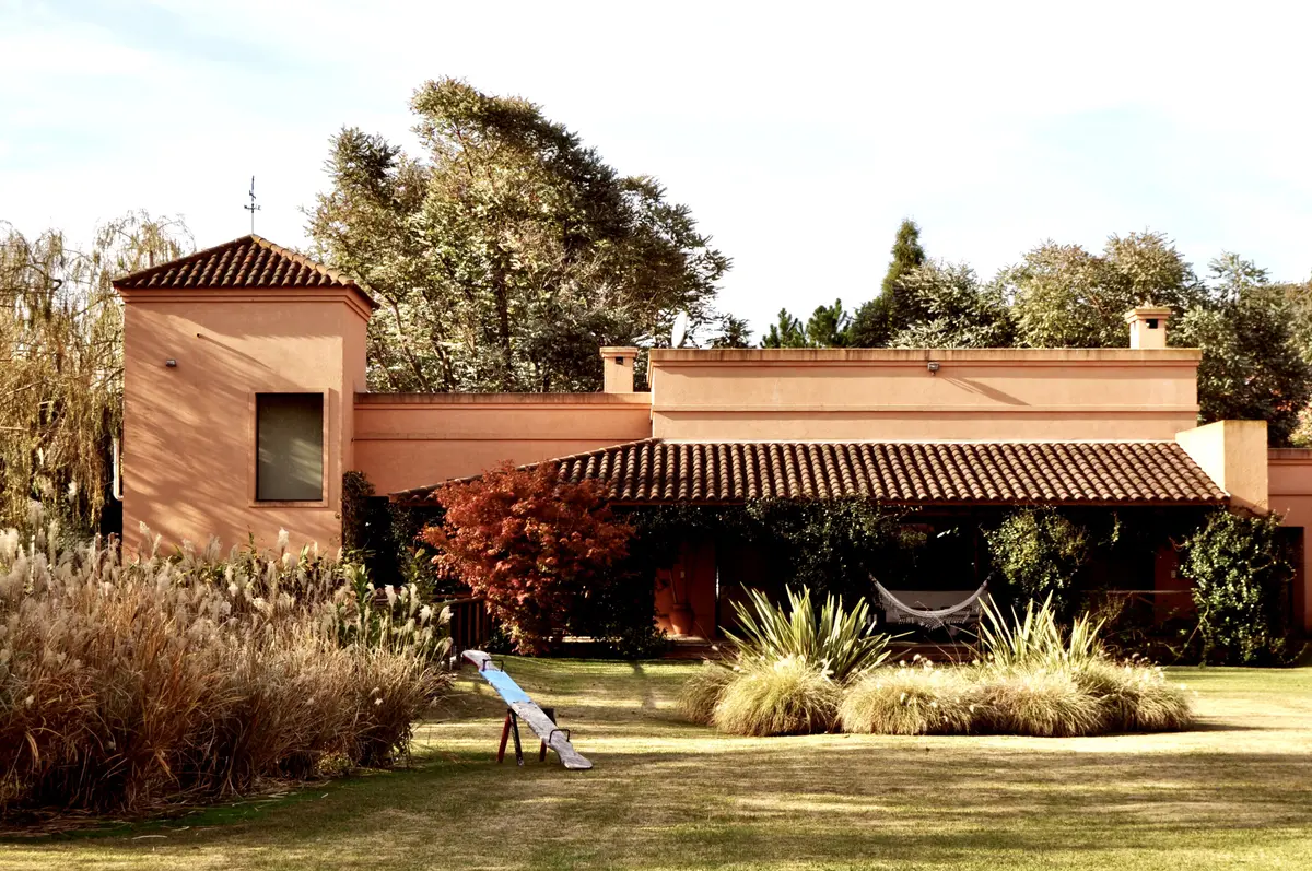 Casa terracota con pergola, jardin y pasto verde abundante — proyecto La Retama, por Marconi Silva Arquitectos, en Manzanares