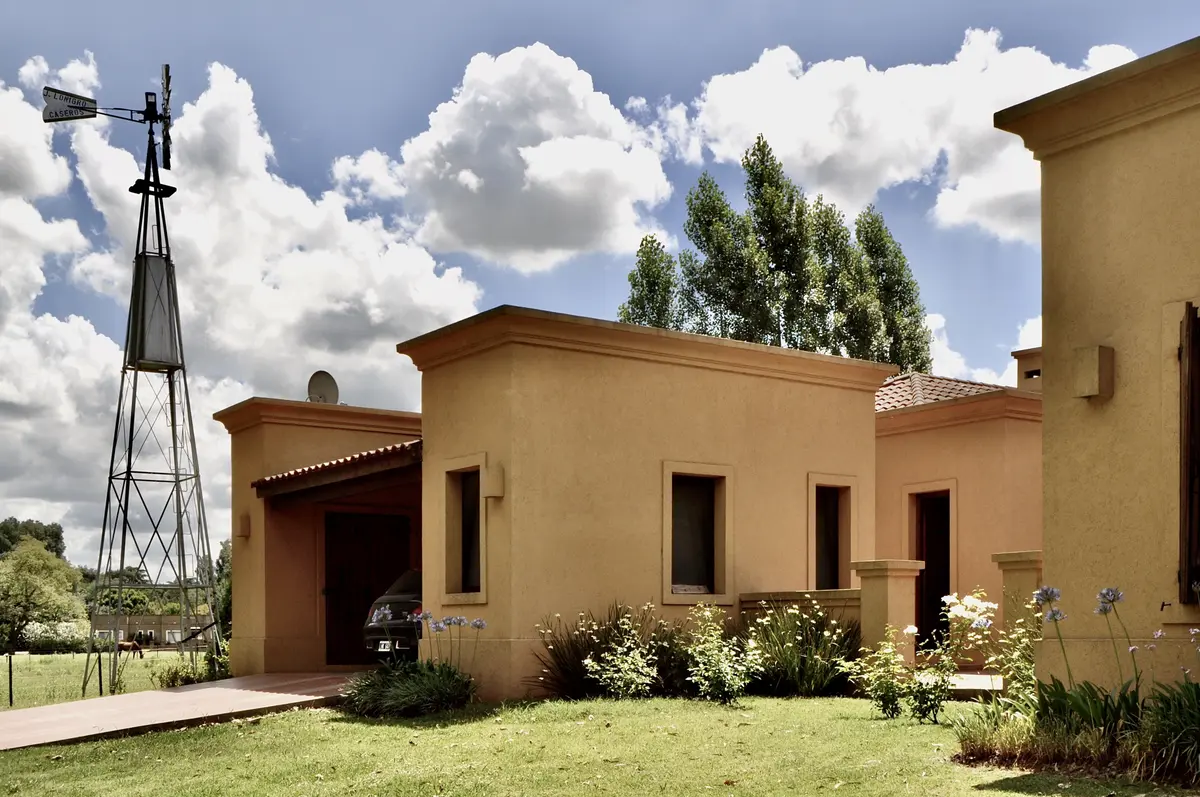 Casa de campo con fachada terracota y molino de viento al fondo — proyecto La Retama 2, por Marconi Silva Arquitectos, en Manzanares