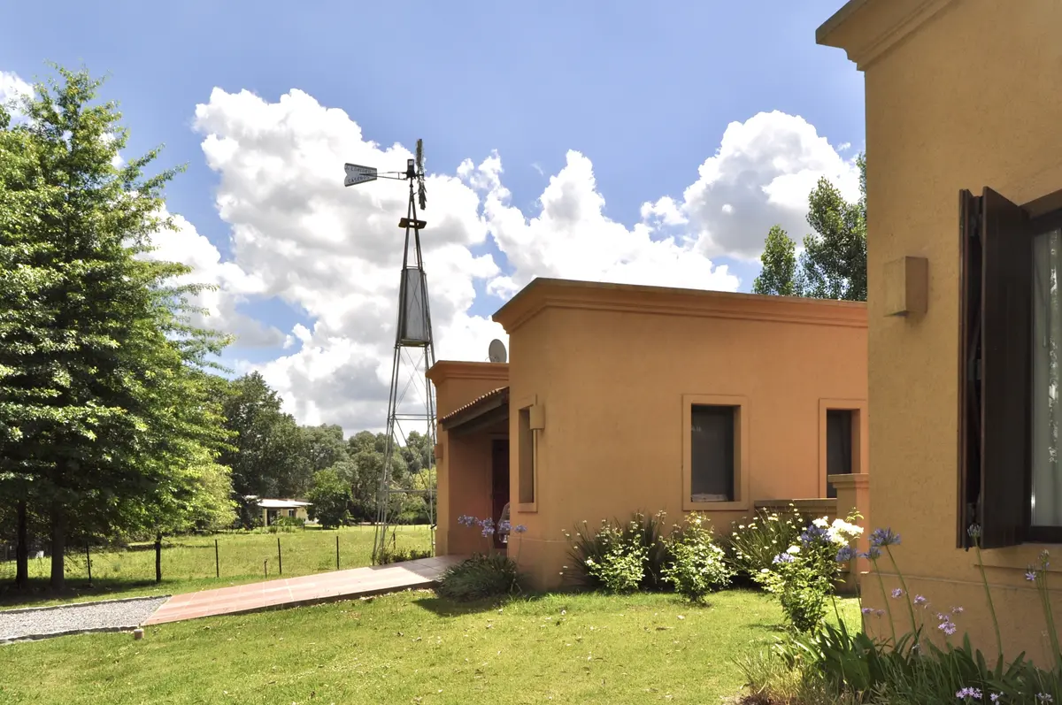 Casa terracota con galeria y molino en jardin verde — proyecto La Retama 2, por Marconi Silva Arquitectos, en Manzanares
