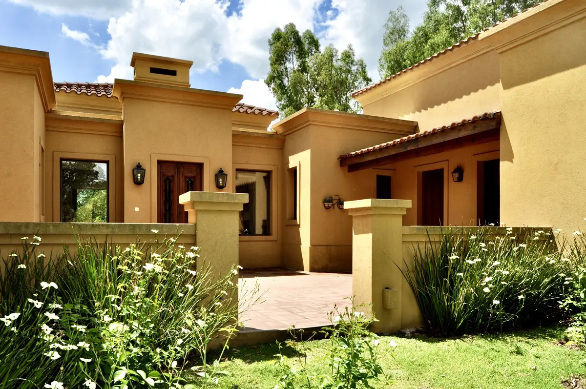 Casa color beige con pergola, jardineras y plantas verdes — proyecto La Retama 2, por Marconi Silva Arquitectos, en Manzanares