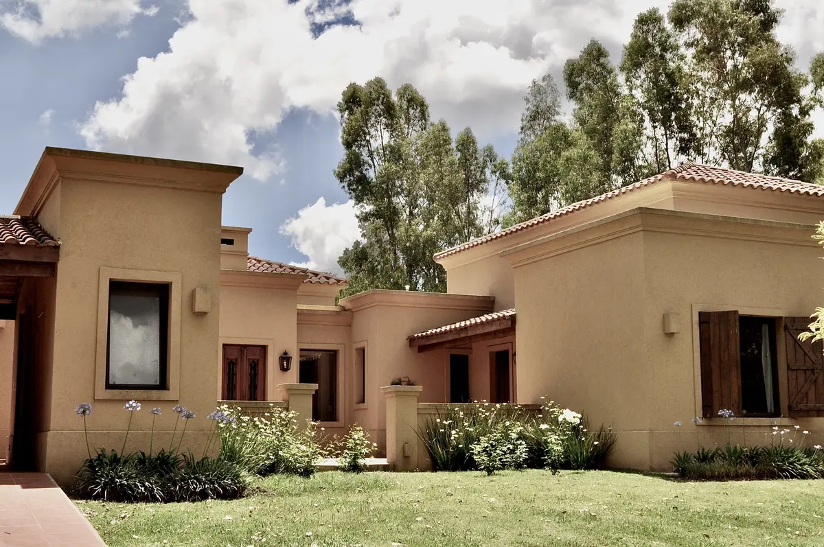 Casa beige de arquitectura contemporanea con jardin y arboles altos — proyecto La Retama 2, por Marconi Silva Arquitectos, en Manzanares