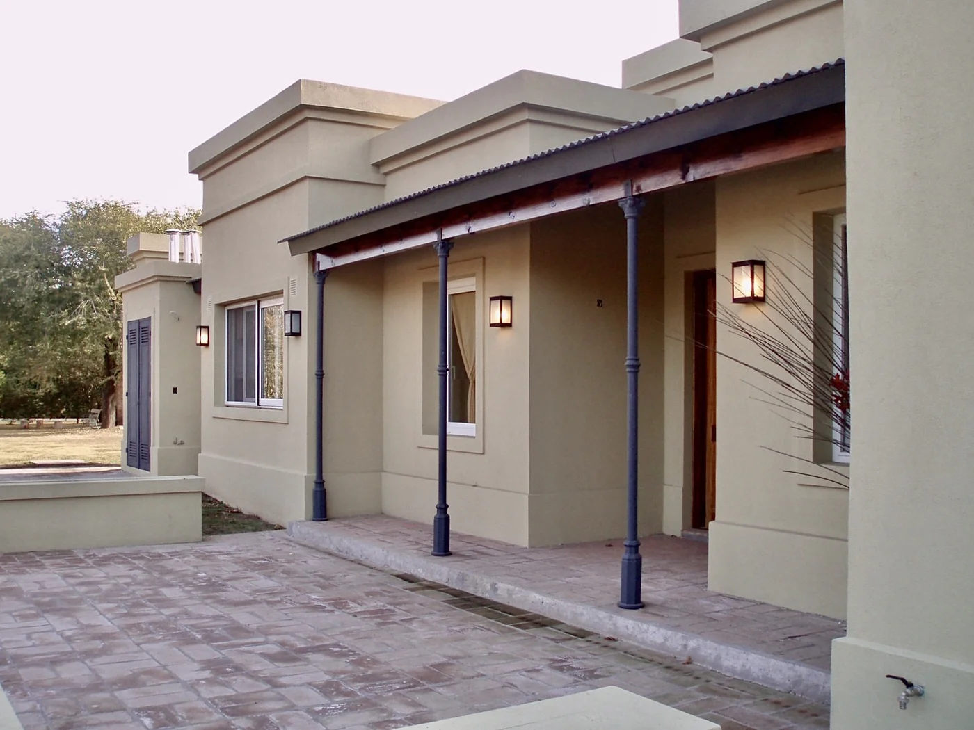 Fachada moderna con galerías, columnas negras y piso de piedra gris.