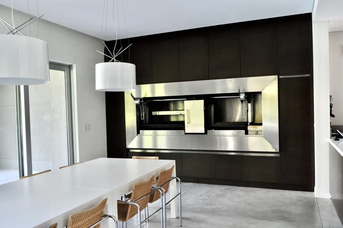 Cocina moderna negra con isla blanca y iluminación led integrada — proyecto Martindale Country Club, por Marconi Silva Arquitectos, en Pilar