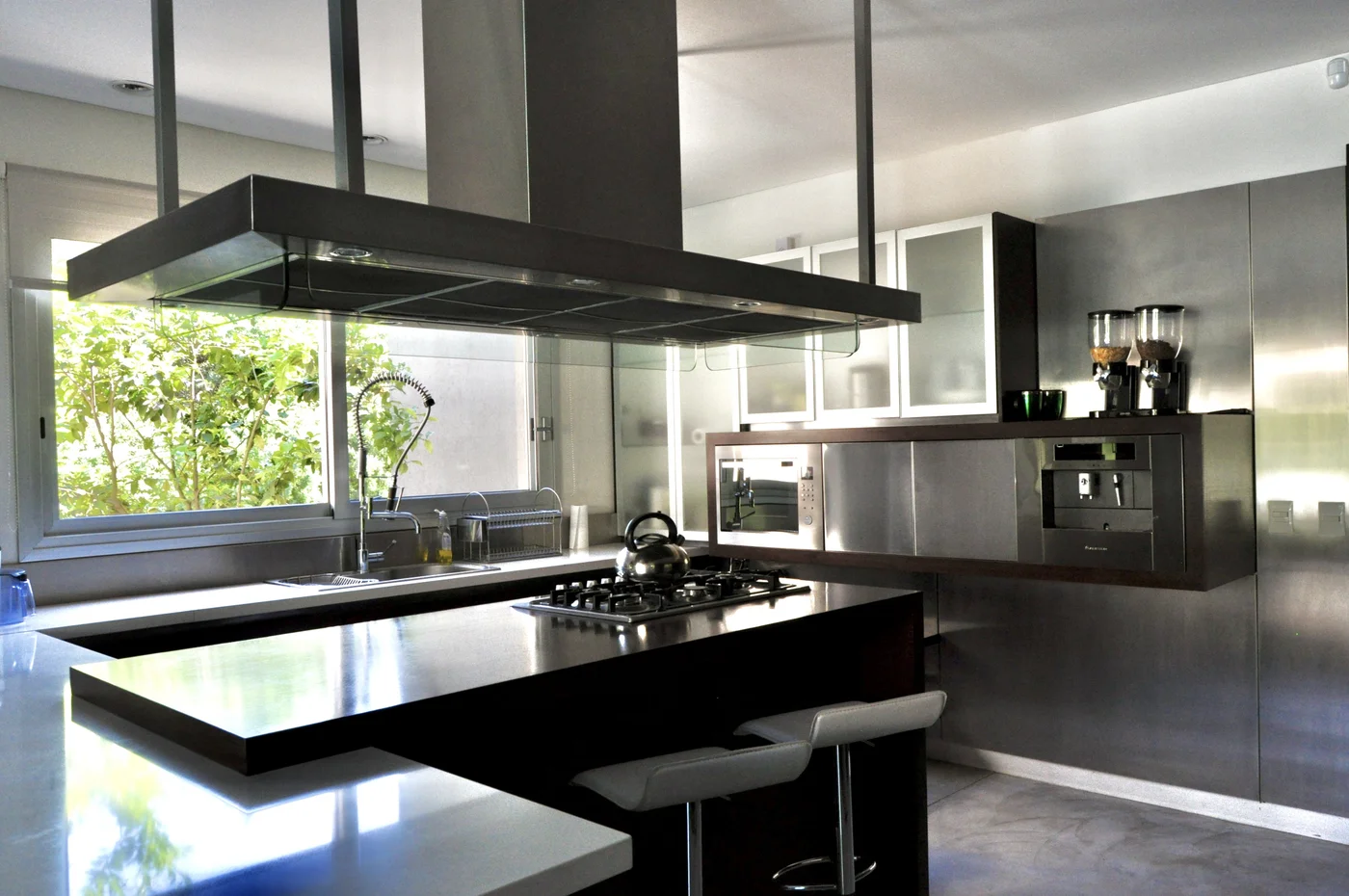 Cocina minimalista con isla negra y ventanal panorámico al jardín