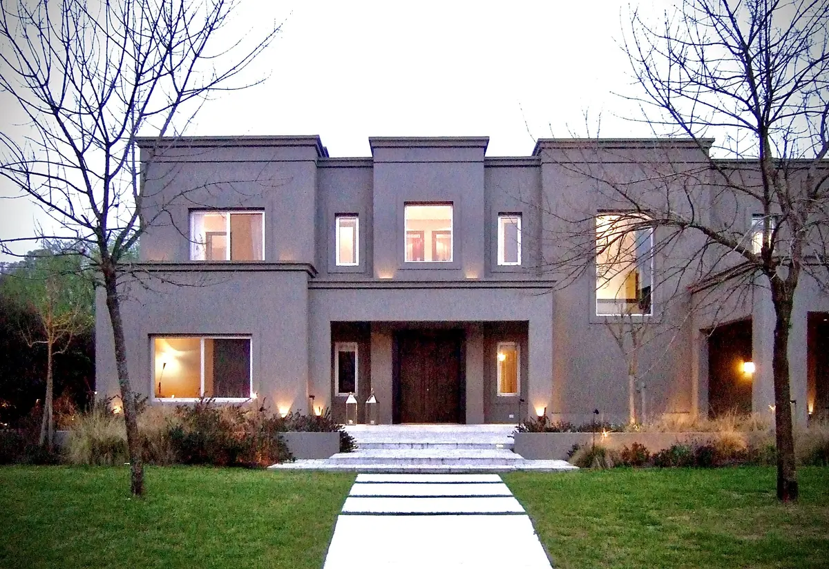 Casa contemporánea gris con fachada simétrica y jardín frontal iluminado — proyecto Martindale Country Club, por Marconi Silva Arquitectos, en Pilar