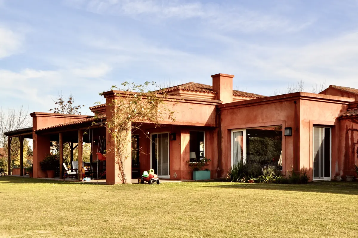 Casa moderna terracota con galería, grandes ventanales y jardín verde — proyecto San Francisco 1, por Marconi Silva Arquitectos, en Manzanares