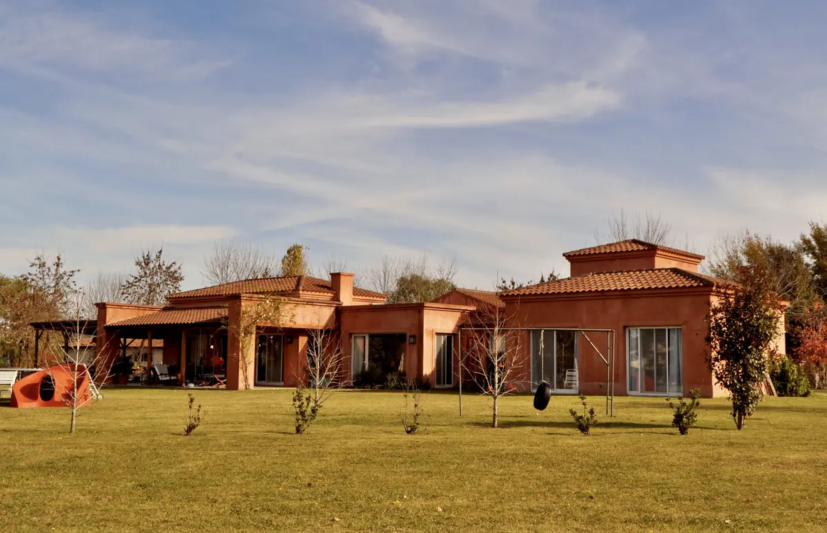 Casa de campo moderna con fachada terracota y jardín amplio — proyecto San Francisco 1, por Marconi Silva Arquitectos, en Manzanares