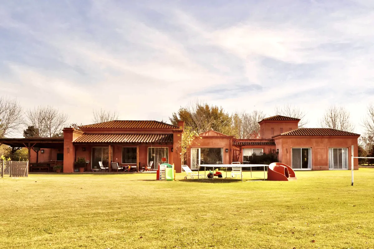 Casa de estancia con fachada terracota y amplio jardín verde — proyecto San Francisco 1, por Marconi Silva Arquitectos, en Manzanares