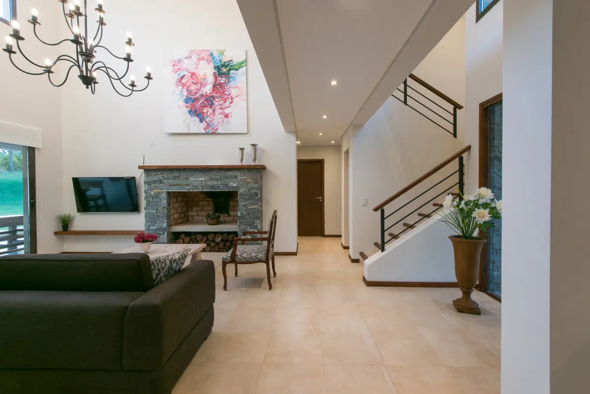 Living moderno de doble altura con escalera flotante — proyecto Costa Esmeralda 2, por Arquitecto Caceres, en Costa Esmeralda