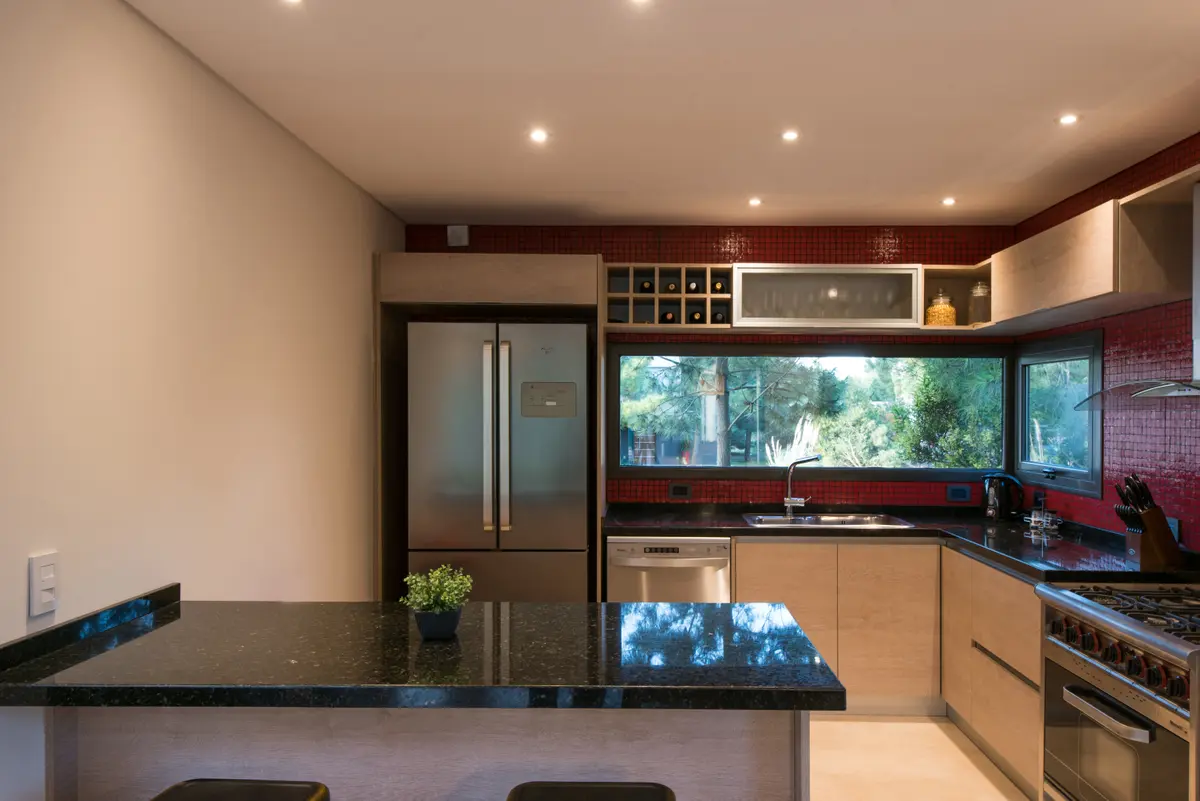 Cocina moderna con isla, ventanas amplias y acabados en madera — proyecto Costa Esmeralda 2, por Arquitecto Caceres, en Costa Esmeralda