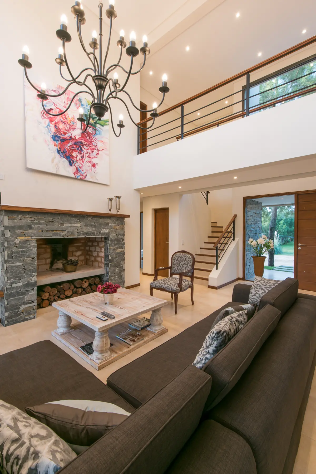 Living amplio de doble altura con chimenea y araña prominente — proyecto Costa Esmeralda 2, por Arquitecto Caceres, en Costa Esmeralda