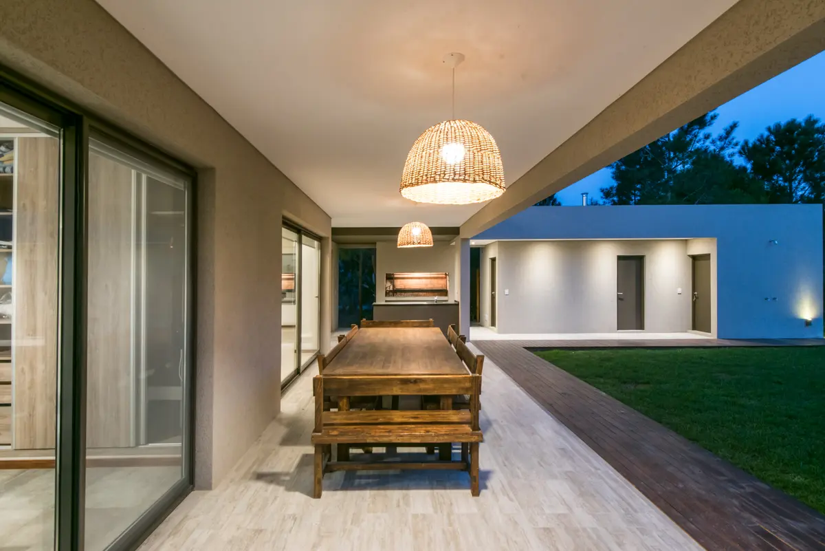 Área de jantar externa coberta com lustre de vime e mesa de madeira — projeto Costa Esmeralda 2, por Arquitecto Caceres, em Costa Esmeralda