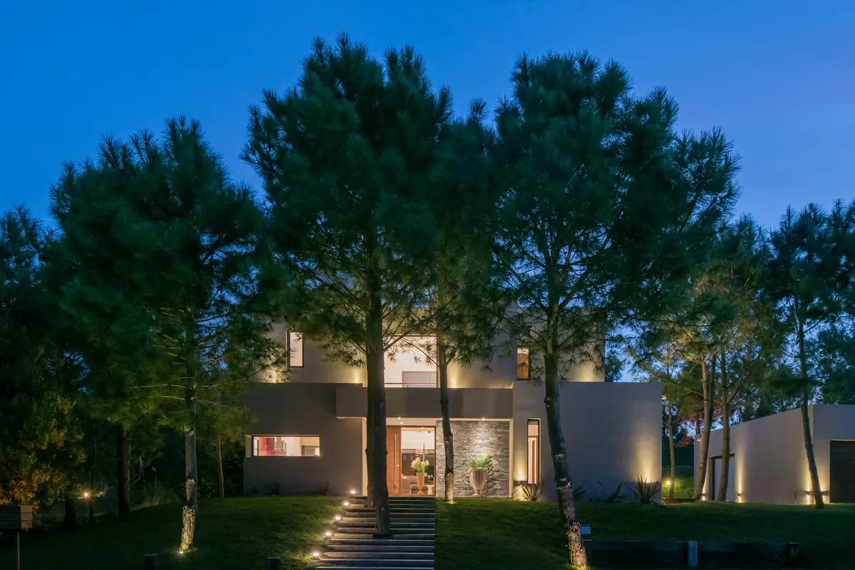 fachada moderna com iluminação ambiente e vegetação proeminente — projeto Costa Esmeralda 2, por Arquitecto Caceres, em Costa Esmeralda