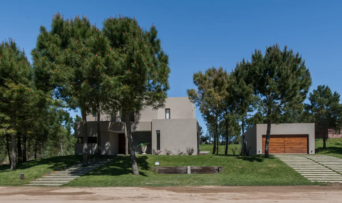 Casa moderna cinza com amplas janelas e vegetação exuberante — projeto Costa Esmeralda 2, por Arquitecto Caceres, em Costa Esmeralda