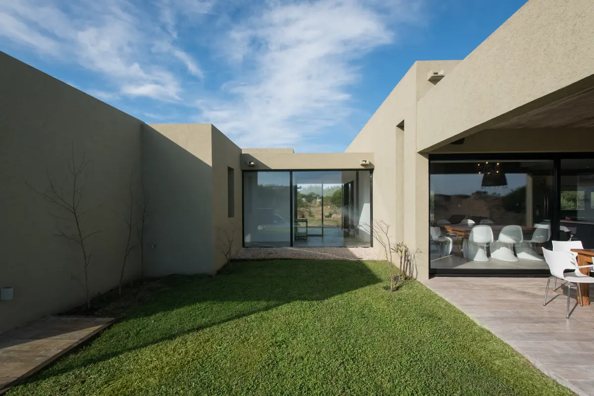Casa moderna em L com pátio interno e deck de madeira — projeto Costa Esmeralda 3, por Arquitecto Caceres, em Costa Esmeralda