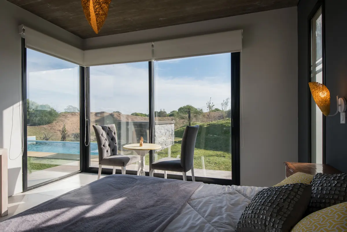 Dormitorio moderno con vista a campo y luz natural abundante — proyecto Costa Esmeralda 3, por Arquitecto Caceres, en Costa Esmeralda