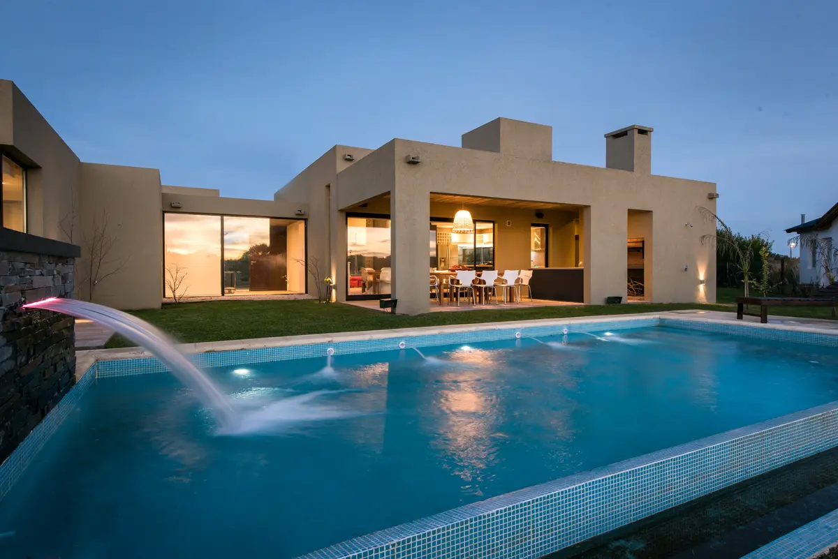 Casa moderna con piscina y luces cálidas al atardecer — proyecto Costa Esmeralda 3, por Arquitecto Caceres, en Costa Esmeralda