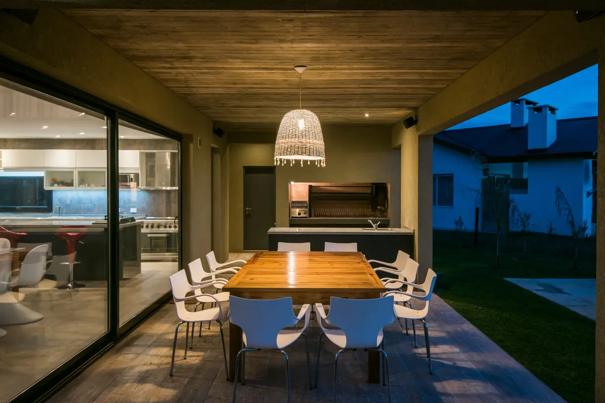 Sala de jantar externa moderna com teto de madeira e churrasqueira — projeto Costa Esmeralda 3, por Arquitecto Caceres, em Costa Esmeralda