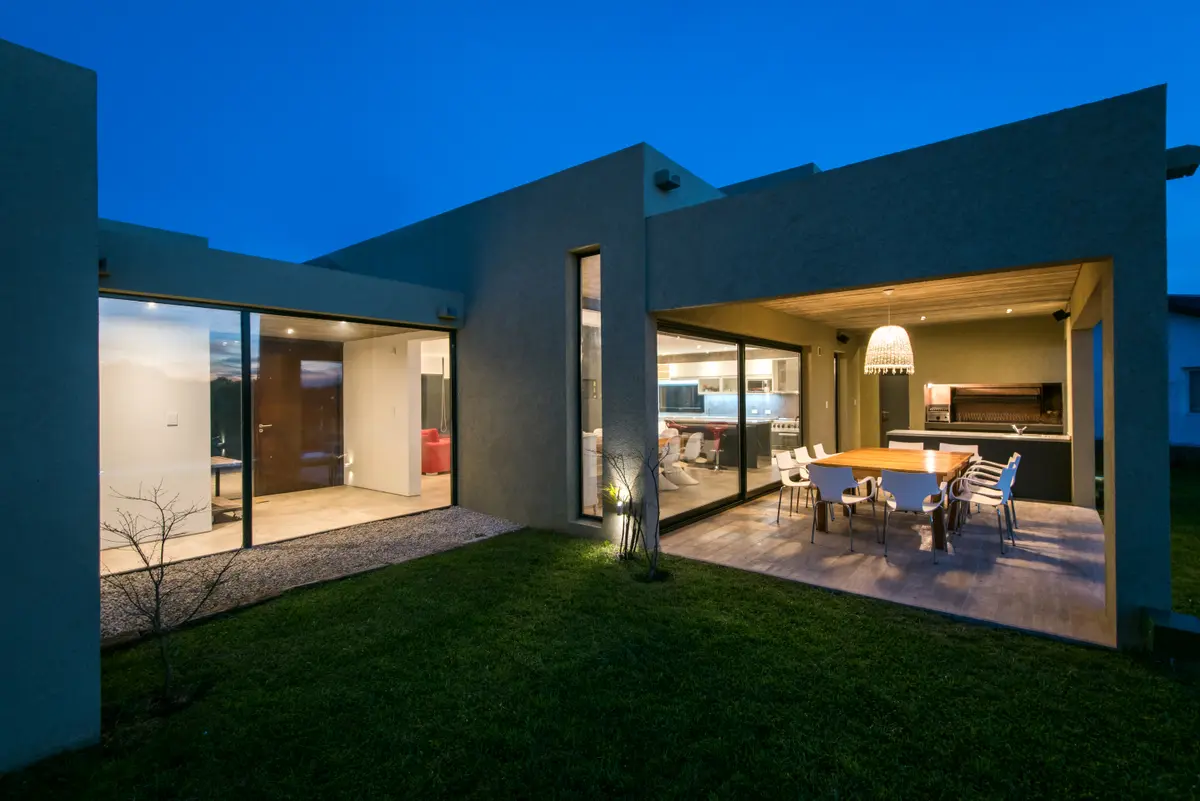 Fachada moderna branca com luzes quentes e sala de jantar externa — projeto Costa Esmeralda 3, por Arquitecto Caceres, em Costa Esmeralda