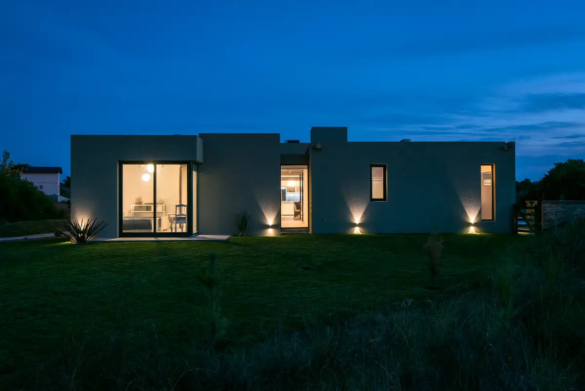 Fachada moderna de casa minimalista iluminada à noite — projeto Costa Esmeralda 3, por Arquitecto Caceres, em Costa Esmeralda