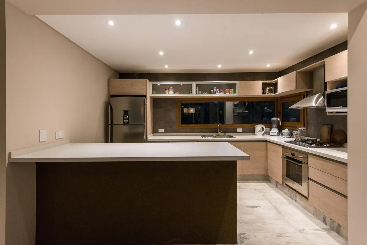 Cocina moderna con isla, muebles de madera y suelo de mármol — proyecto Costa Esmeralda Casa MAI Lote 374 Deportiva, por Arquitecto Caceres, en Costa Esmeralda