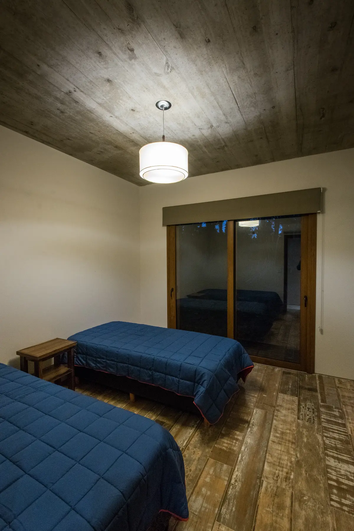 dormitorio moderno con techo de hormigón y suelo de madera rústica — proyecto Costa Esmeralda Casa MAI Lote 374 Deportiva, por Arquitecto Caceres, en Costa Esmeralda