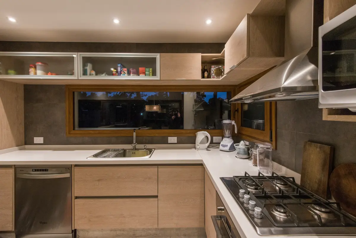 Cocina moderna con muebles de madera y ventana amplia — proyecto Costa Esmeralda Casa MAI Lote 374 Deportiva, por Arquitecto Caceres, en Costa Esmeralda