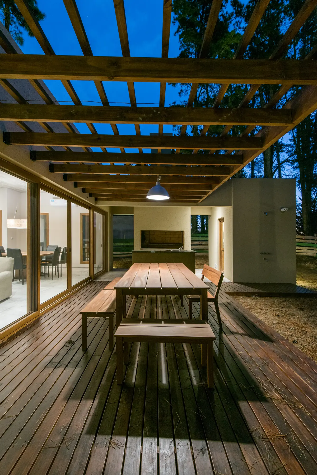 Pátio moderno com pérgola de madeira e deck escuro — projeto Costa Esmeralda Casa MAI Lote 374 Deportiva, por Arquitecto Caceres, em Costa Esmeralda