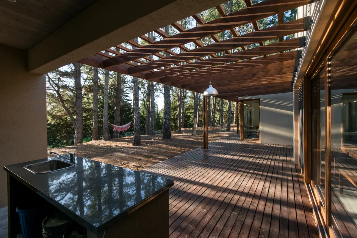 Pátio moderno com pérgola de madeira e vista para a floresta — projeto Costa Esmeralda Casa MAI Lote 374 Deportiva, por Arquitecto Caceres, em Costa Esmeralda