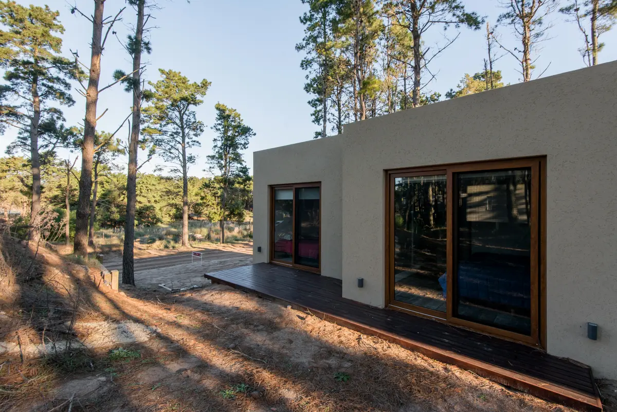Casa moderna com fachada de estuque e madeira em floresta — projeto Costa Esmeralda Casa MAI Lote 374 Deportiva, por Arquitecto Caceres, em Costa Esmeralda