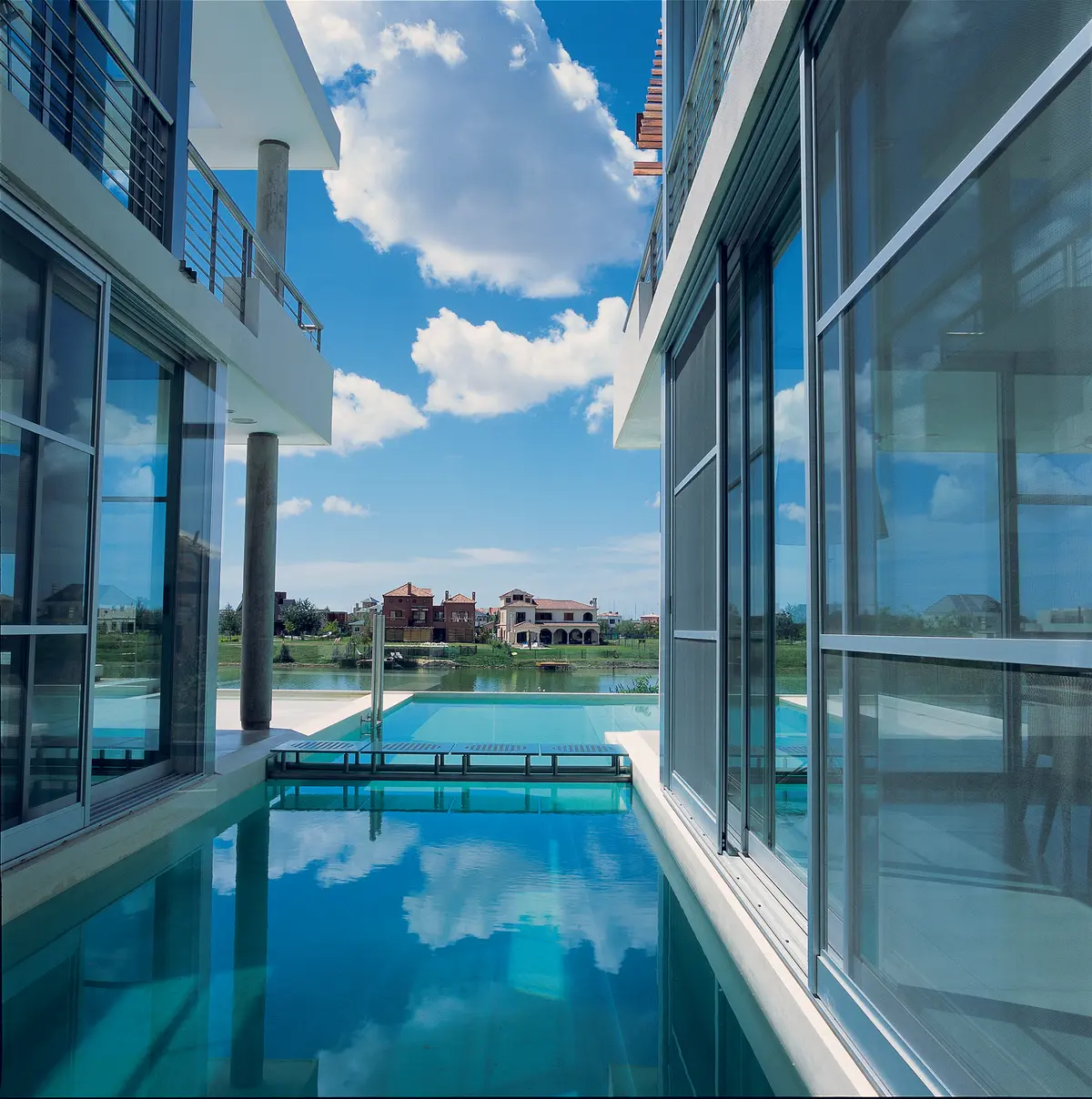 Pileta moderna con reflejos frente a villas mediterráneas — proyecto Casa Hormigon, por Barrionuevo Arquitects, en B1648 Tigre