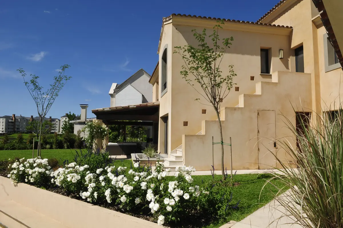 Fachada moderna mediterrânea com flores brancas e pátio coberto — projeto Al agua, por Ricardo Pereyra Iraola, em Nordelta
