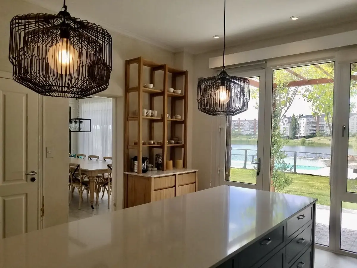 Cocina moderna con isla de mármol y luces colgantes industriales — proyecto Los Castores, Nordelta, por Estudio Moreto Bensusan, en Nordelta