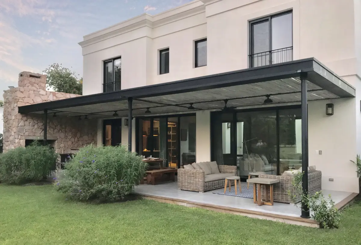 Amplio patio moderno con pérgola, muebles de exterior y jardín — proyecto Barrio Mayling, por Estudio Moreto Bensusan, en Pilar