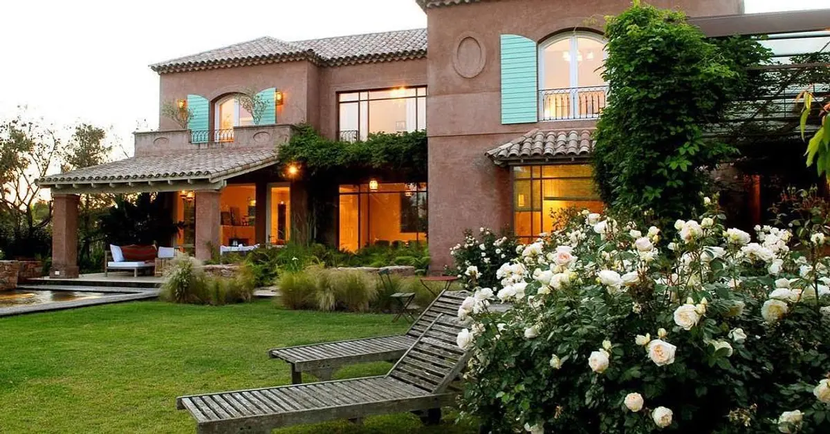 fachada de casa mediterrânea com jardim exuberante — projeto Laguna del Sol, por Estudio Moreto Bensusan, em Tigre